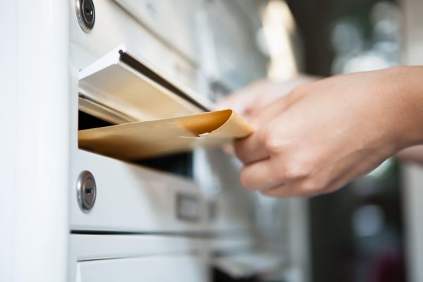 Frau, die Brief in Briefkasten einwirft